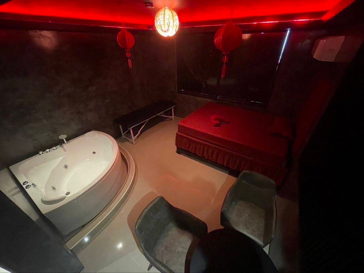 A private room at Amor 888: a whirlpool bath, a bed with red covers and red lanterns under a red-lit ceiling