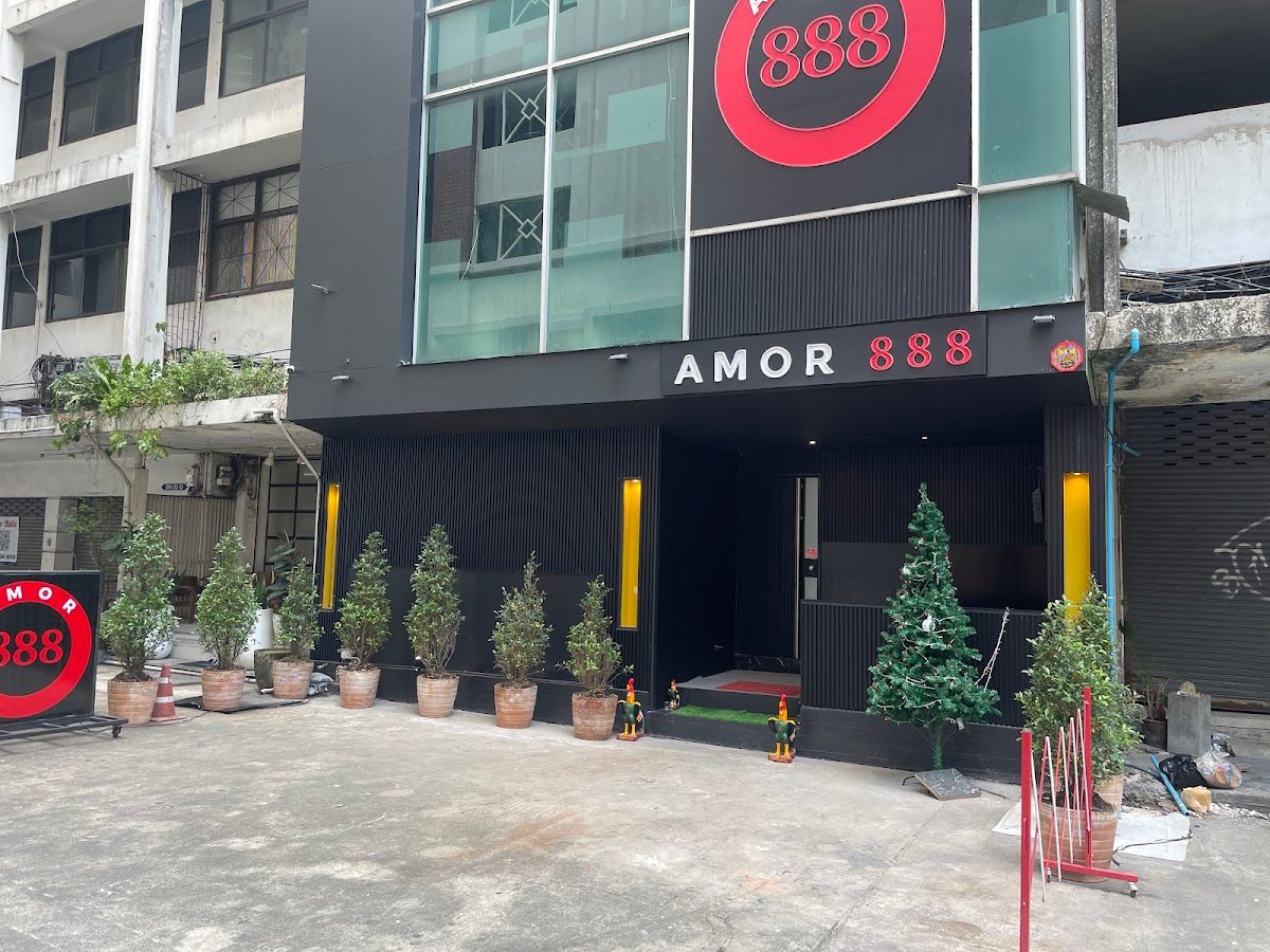 Amor 888 by day: the black front with the red 888 sign and potted trees along the entrance at 390/35 Sukhumvit Soi 18